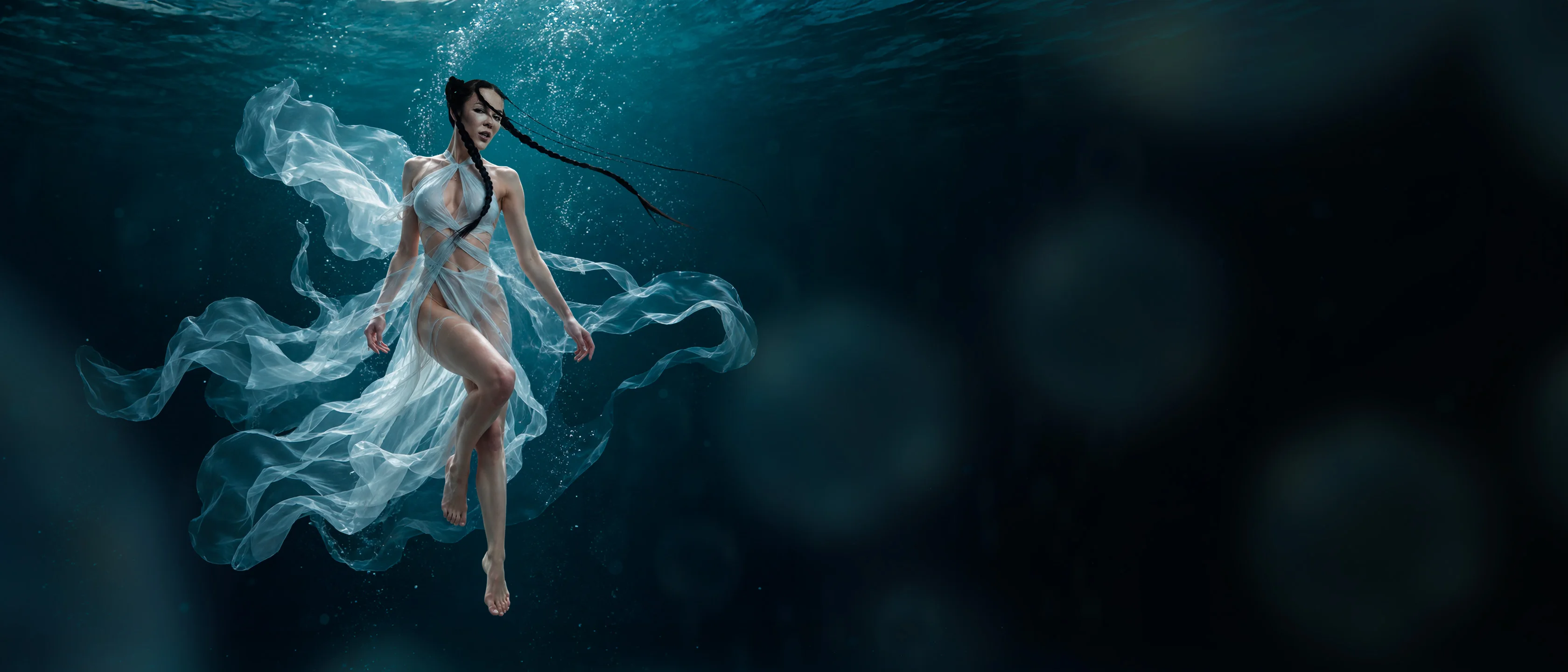 A dancer in flowing sheer fabric, floating underwater